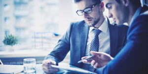 Image of two young businessmen discussing project at meeting